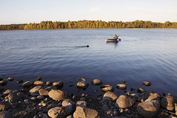 The hunter by the boat in the middle of the lake, to it floats a — Stock Photo, Image