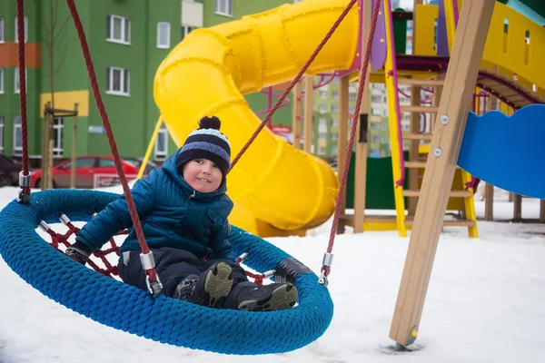 Drie jaar jongen spelen op de speelplaats in de winter — Stockfoto