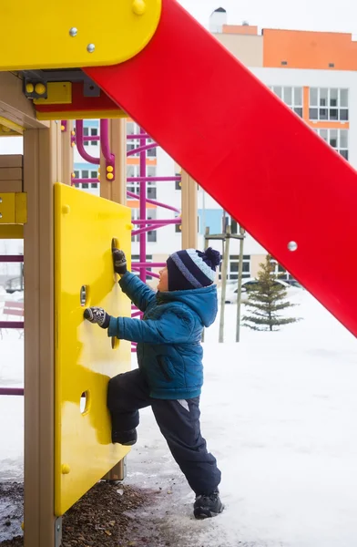 Jongetje van drie jaar spelen op de speelplaats in de winter — Stockfoto