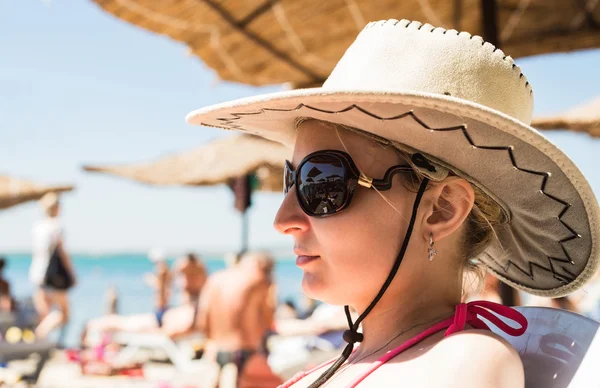 Девушка в шляпе с большими полями, загорающими на пляже — стоковое фото