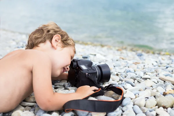 Little photographer on beach taking pictures sea — Stock Photo, Image