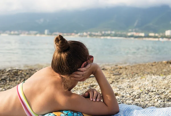 Girl sunbathes and looks at sea — Stock Photo, Image