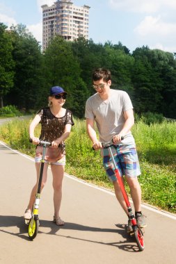 Genç olumlu atletik çift sürme scooter Şehir Parkı