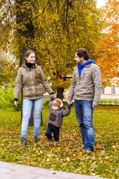 Ung familj promenader med liten son i höst park — Stockfoto