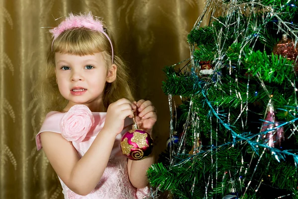 Meisje in roze gedecoreerde kerstboom — Stockfoto