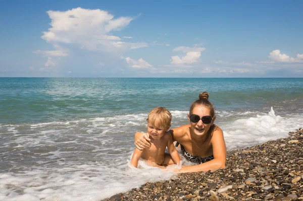 Moeder met kind leugen in zee golven — Stockfoto