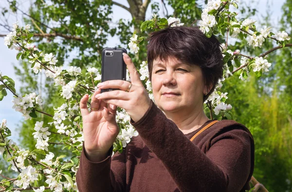 Vrouw foto's zelf tegen bloeiende apple — Stockfoto