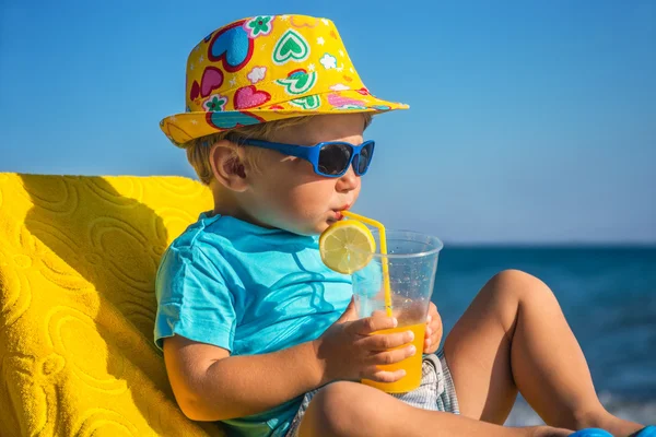 Kid drinks juice against sea — Stock Photo, Image