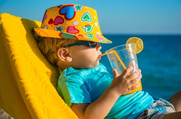 Jongen kid in fauteuil met SAP glas op strand — Stockfoto