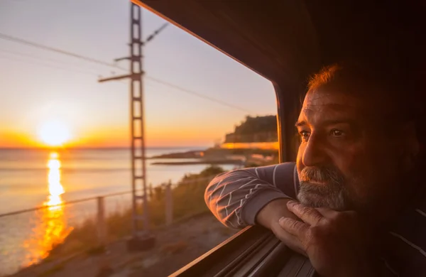 Homem admira pôr do sol do mar do trem — Fotografia de Stock