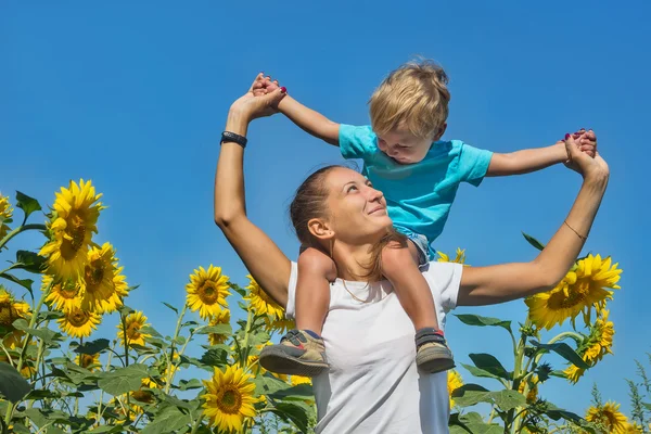 Small son with mum among sunflowers — Stock Photo, Image