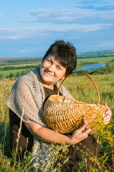 Attractive woman with basket on meadow — Stock Photo, Image