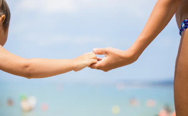 Baby hand in moeder hand op een achtergrond van de zee — Stockfoto