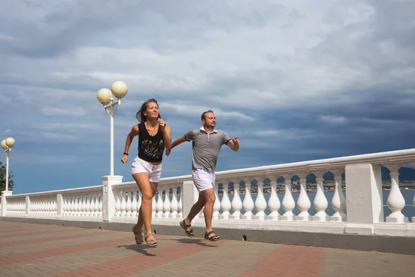 Joven pareja deportiva corre a lo largo del paseo marítimo — Foto de Stock