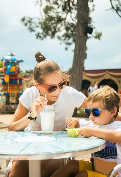 Ung kvinna lille son vid bordet i café i nöjesparken — Stockfoto