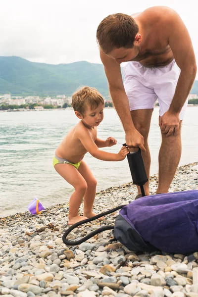 Kleine jongen helpen vader opgeblazen luchtbed zwemmen in zee — Stockfoto