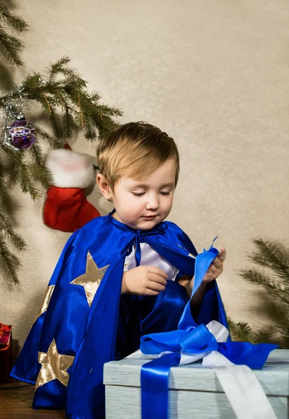 Dziecko w stroju nowego roku otwierając prezent na Boże Narodzenie — Zdjęcie stockowe