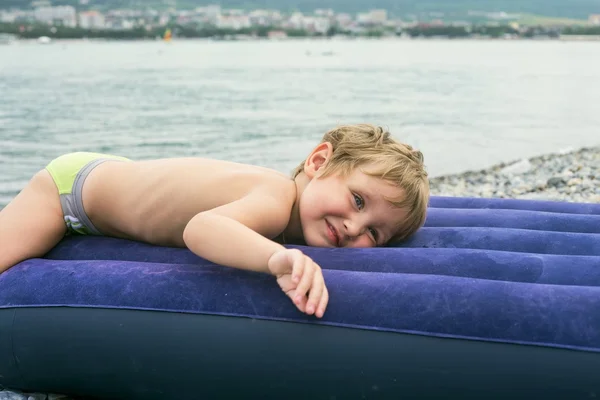 Menino no colchão inflável perto do mar — Fotografia de Stock