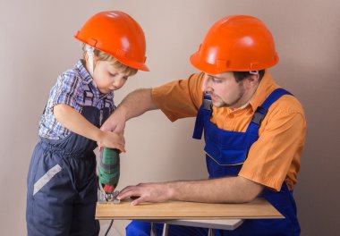 Baba koruyucu kask çalışma jigsaw genç oğlu ile