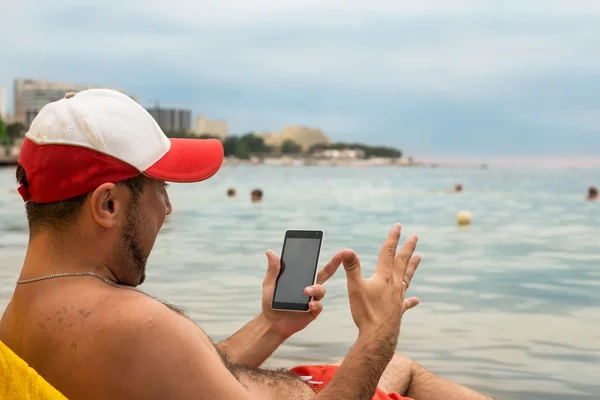 Emocjonalne człowieka z telefonem w ręku na plaży w nadmorskim kurorcie — Zdjęcie stockowe