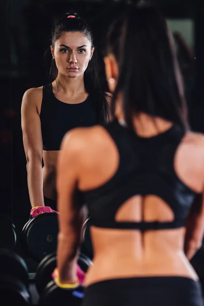 Young woman choosing dumbbells in gym — Stock Photo, Image