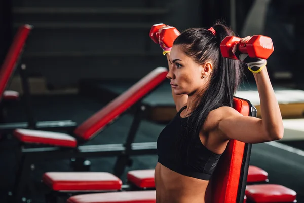 Молода спортивна жінка робить вправи з гантелями в спортзалі — стокове фото