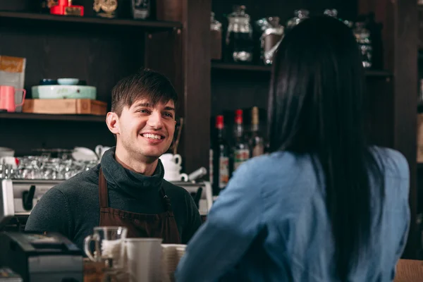 Чоловік касир посміхається для молодої жінки в кафе — стокове фото