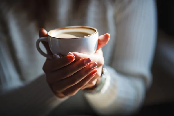 Woman holds hot cup of coffee, warming her hands — Stock Photo, Image