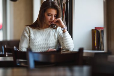 kadın pencere yakınındaki kafede kitap okumak