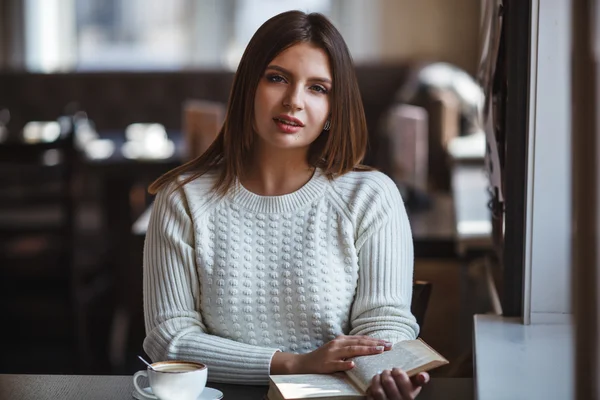 Woman reading book at cafe near window — Stock Photo, Image