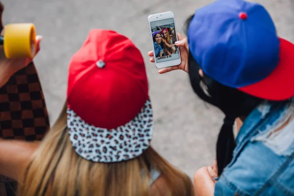 Duas meninas olhando eles fotos no smartphone — Fotografia de Stock