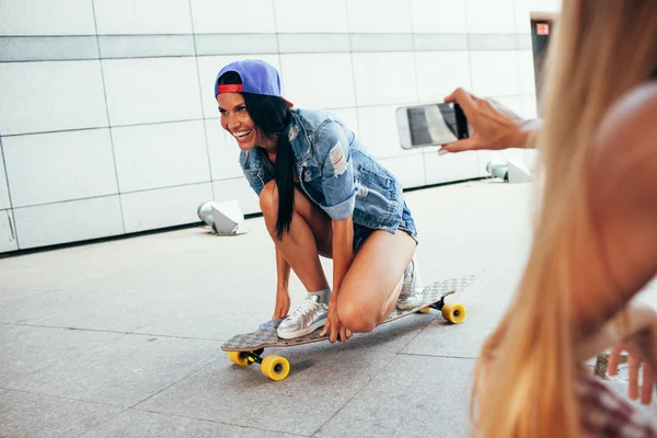 Uma mulher atirando outra em longboard — Fotografia de Stock