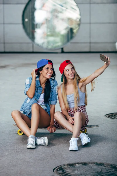 longboard üzerinde oturan iki genç kız