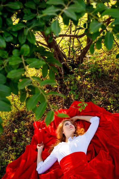 Woman in red skirt lying under the tree — Stock Photo, Image