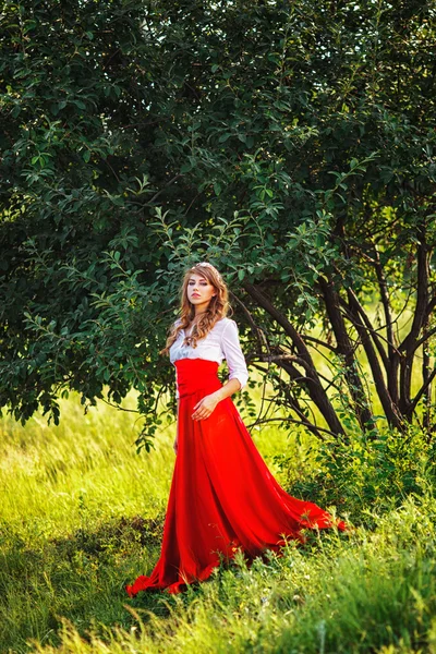 Mujer en falda roja de pie debajo del árbol —  Fotos de Stock