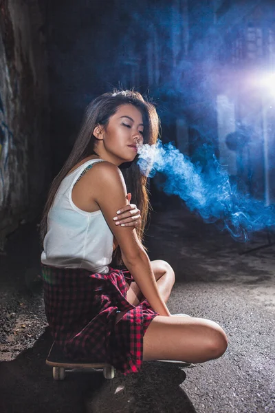 Asiático mujer sentado en skate y fumar — Foto de Stock