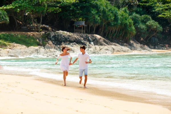 Casal feliz correndo na praia tropical — Fotografia de Stock