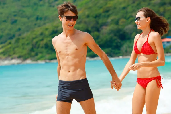 Casal feliz em óculos de sol na praia — Fotografia de Stock