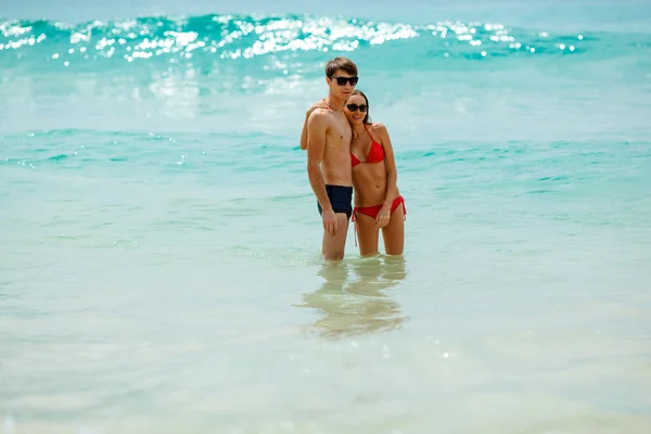 Casal feliz usando óculos de sol na água do mar — Fotografia de Stock