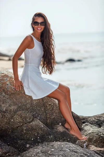 Beautiful tanned woman sitting on stone — Stock Photo, Image