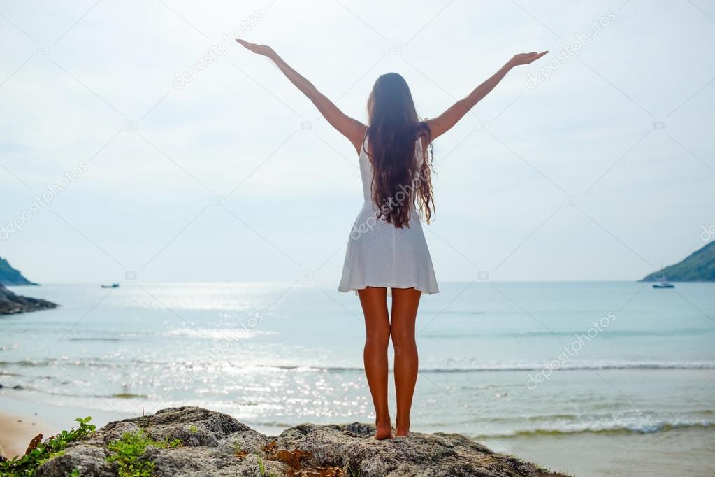 woman stands on rocks in front of the ocean