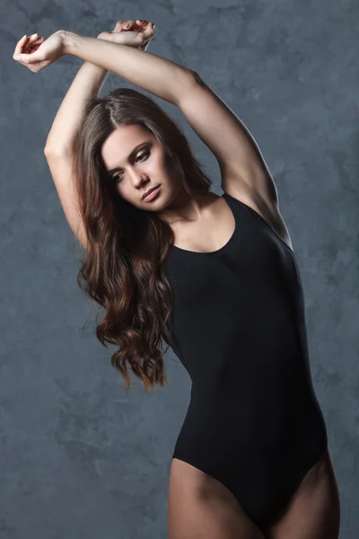 Woman in black leotard posing on grey background — Stock Photo, Image