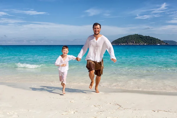 พ่อและลูกชายที่มีความสุขวิ่งไปด้วยกันที่ชายหาด — ภาพถ่ายสต็อก