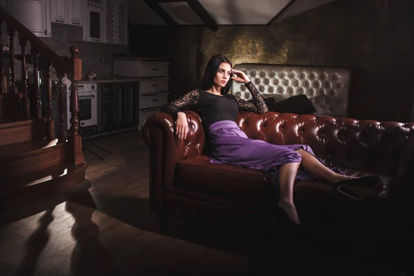 Schöne luxuriöse Frau sitzt auf einem ledernen Vintage-Sofa — Stockfoto