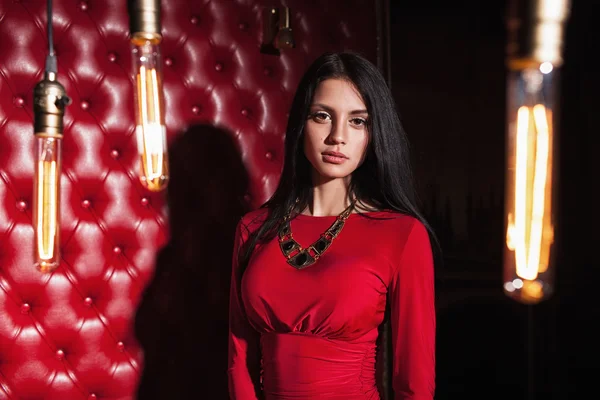 Młoda kobieta w czerwonej sukience stojąca przy ścianie — Zdjęcie stockowe