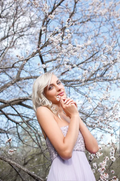 Blond kvinna i en blomstrande trädgård — Stockfoto