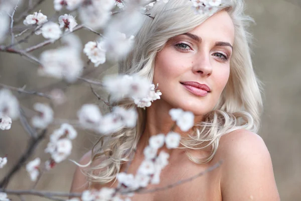 Blondi nainen kukoistavassa puutarhassa — kuvapankkivalokuva