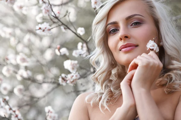 Blonde woman in a flowered garden — Stock Photo, Image