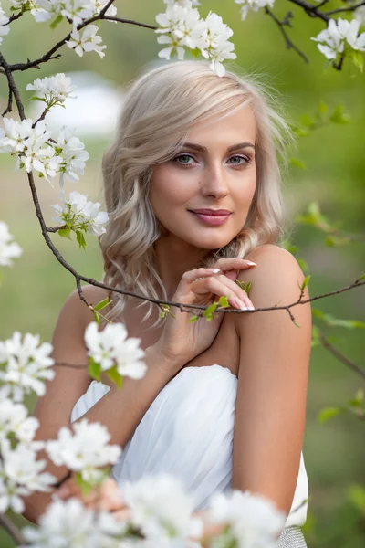 Blonde vrouw in een bloemrijke tuin — Stockfoto