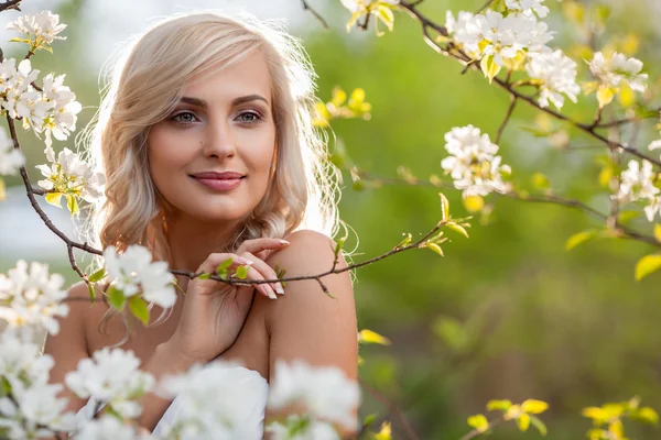 Blonde woman in a flowered garden — Stock Photo, Image